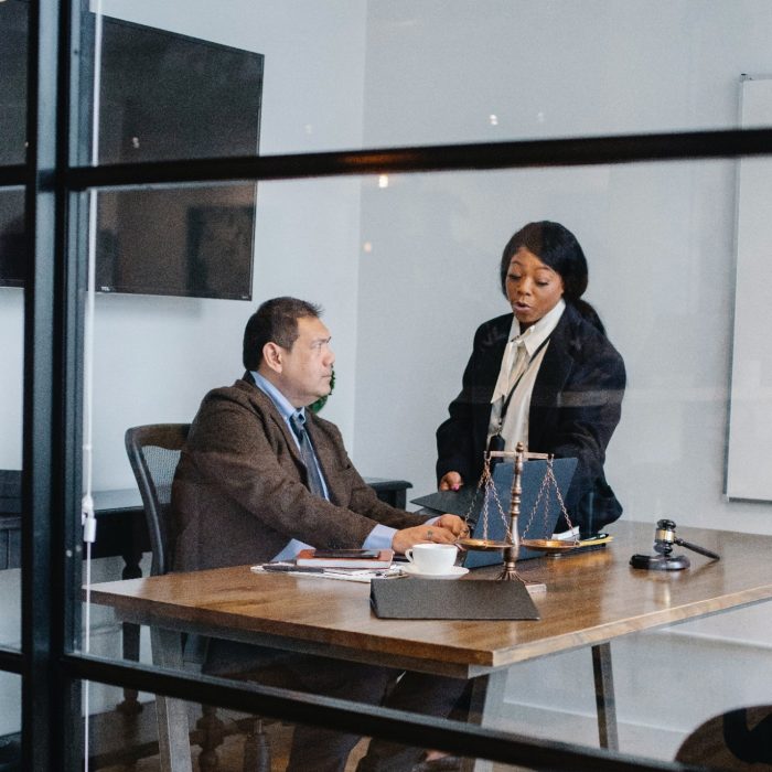 One male and one female solicitor talking at an office desk