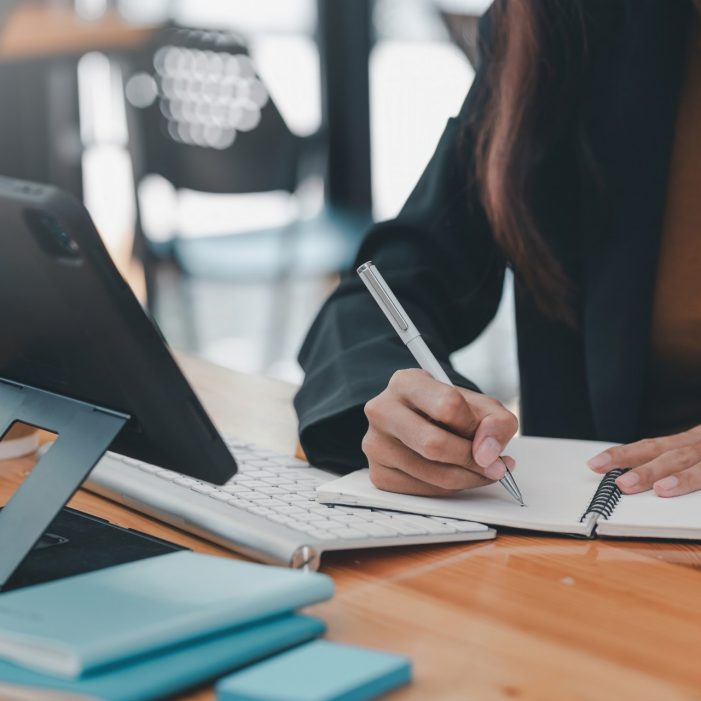 Image of a businesswoman holding a pen and taking notes on work concept.