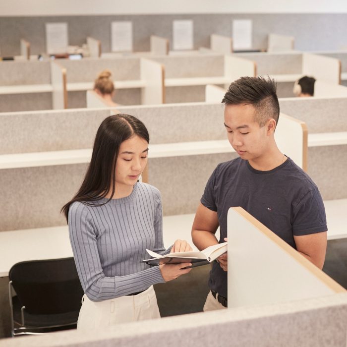 Students walking past bookcases at the law library UNSW.