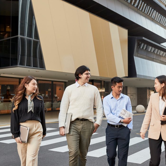 Group of law students walking behind law building, smiling and laughing, smart casual attire