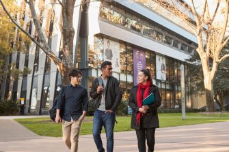 Three Law students walking on Main Wallkway with the Law Building in the background