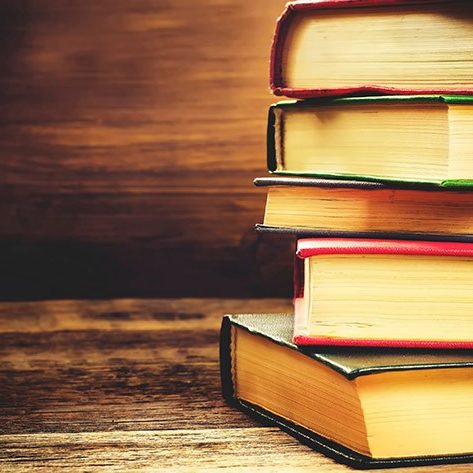 stack of books on the dark wood background. toning. selective focus on the middle book