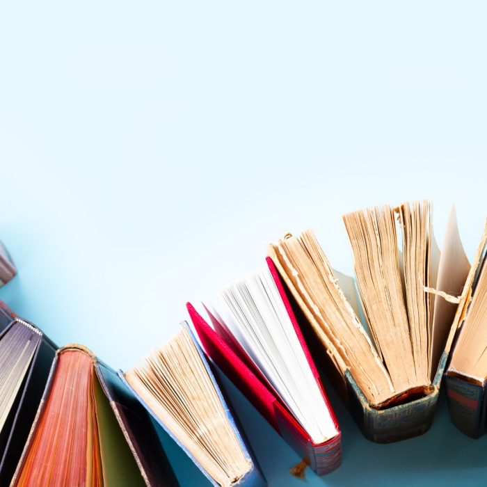 Pile of old books on blue background with copy space