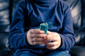 A close up of a a child holding an asthma inhaler