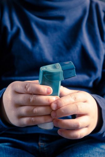 A close up of a a child holding an asthma inhaler