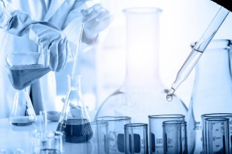 hand of scientist holding flask with lab glassware and test tubes in chemical laboratory background, science laboratory research and development concept