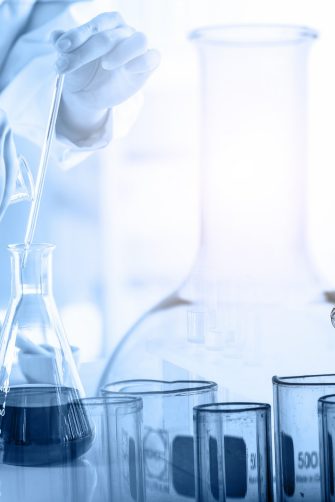 hand of scientist holding flask with lab glassware and test tubes in chemical laboratory background, science laboratory research and development concept