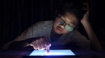 asian-boy-pressing-digital-tablet-at-night-with-serious-face