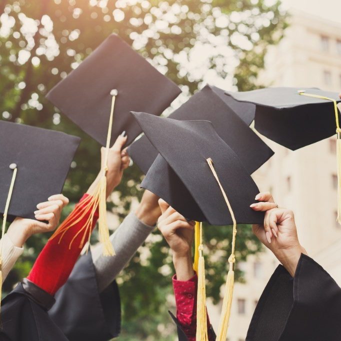 Mortarboards being held in air by graduates