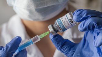 Photo of a hand holding COVID-19 vaccine and syringe