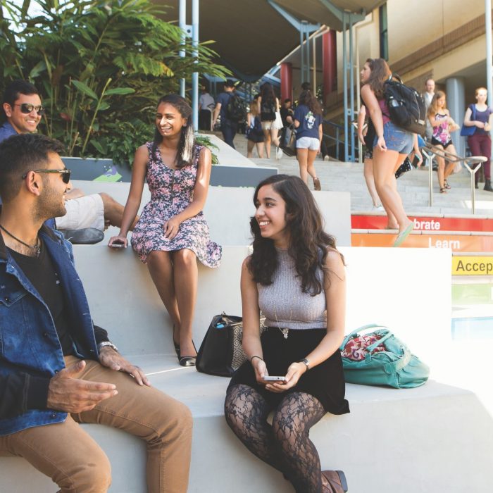 Students sit on the rainbow steps on a sunny day in the Kensington Quad