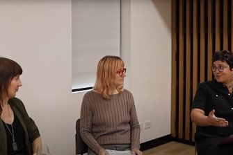 three women are seated, in conversation