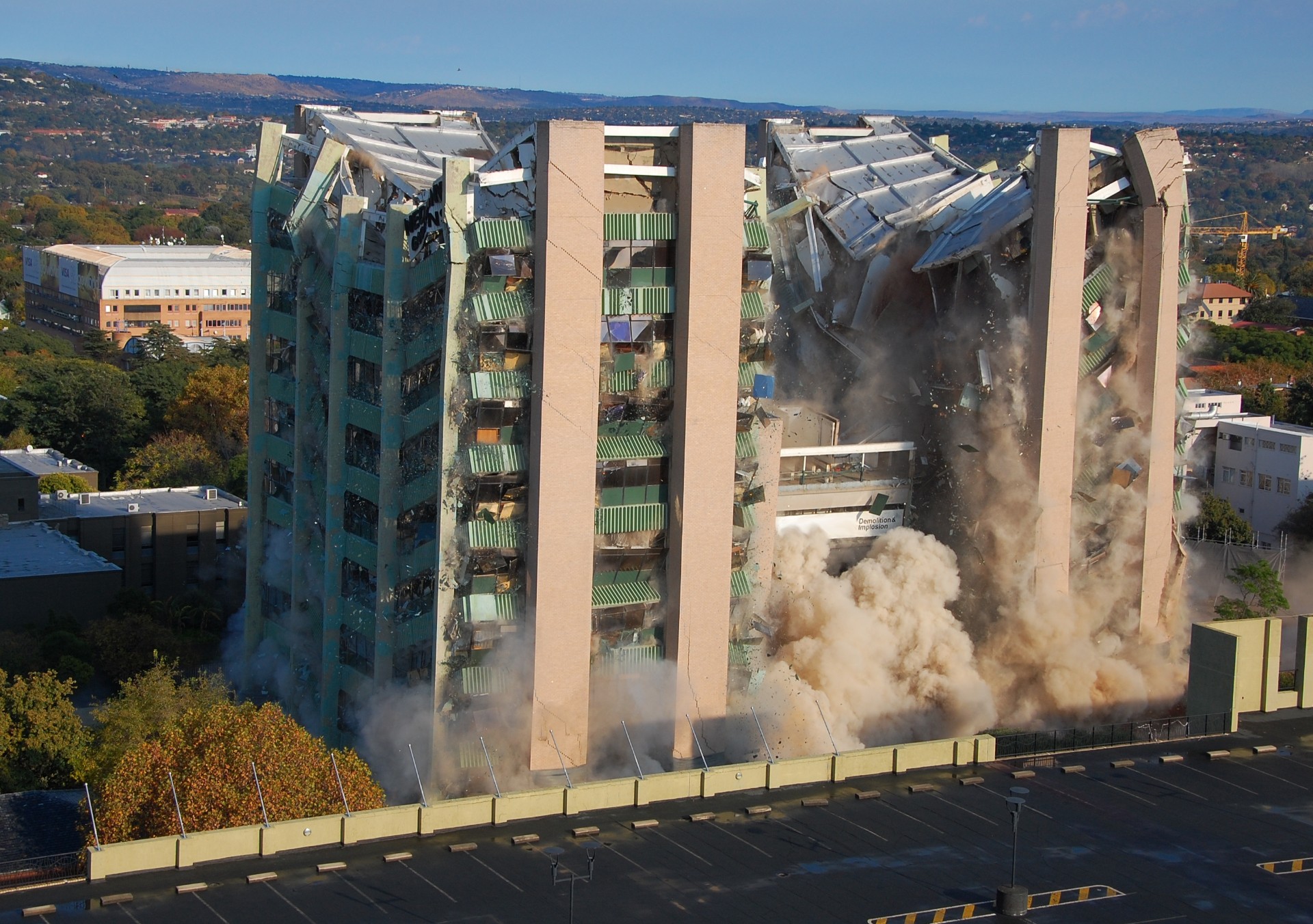 An eight-storey building begins to fall after explosive charges destroy its structural integrity