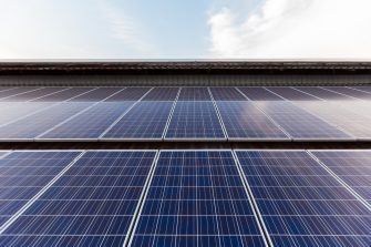 Solar Panel Photovoltaic installation on a Roof of factory, sunny blue sky background, alternative electricity source - Sustainable Resources Concept.