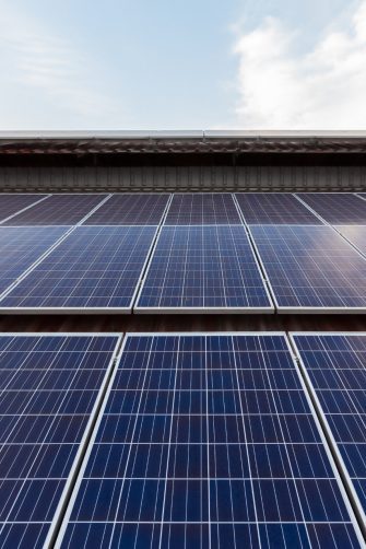 Solar Panel Photovoltaic installation on a Roof of factory, sunny blue sky background, alternative electricity source - Sustainable Resources Concept.