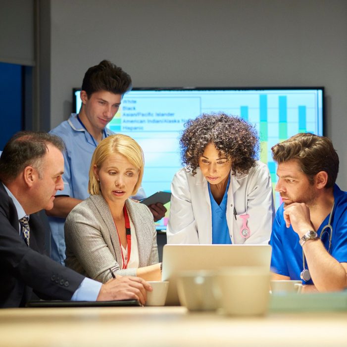 a mixed group of healthcare professional and business people meet around a conference table .