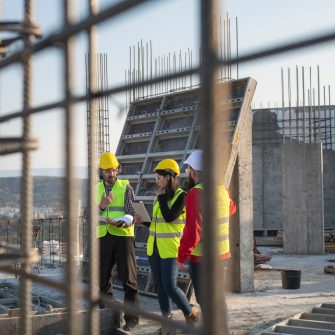 Construction workers standing on outdoor construction site and discuss the building plans