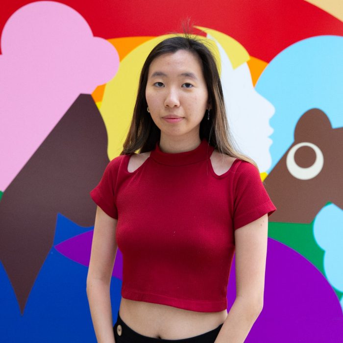 Winnie stands in front of a colourful mural