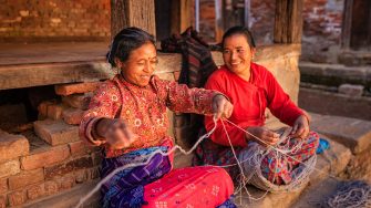 Nepali women spinning a wool in front of the house. Bhaktapur in Kathmandu valley.