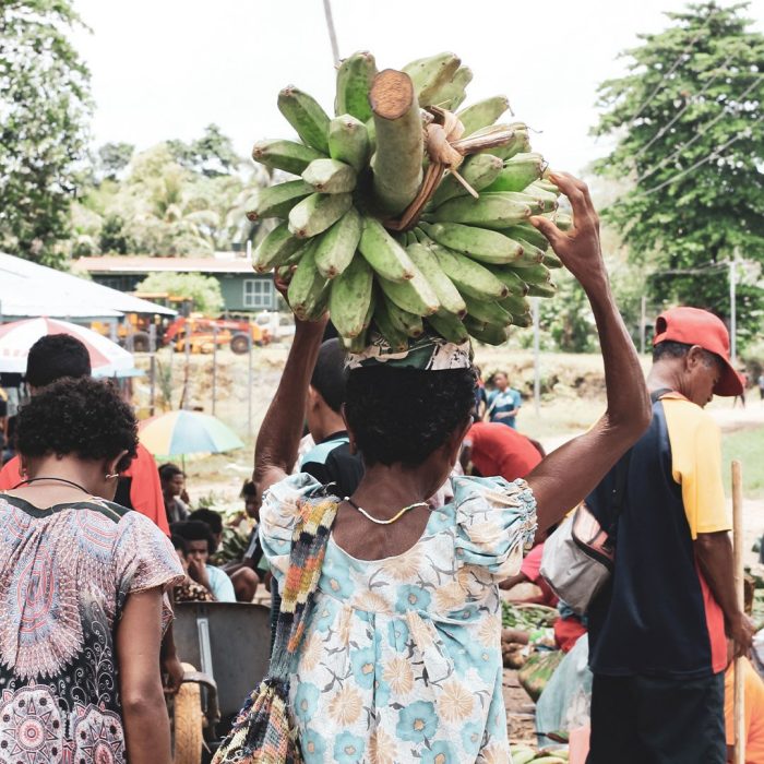 Women in Papua New Guinea are carrying bananas and shopping bags. 