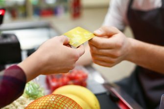 Young woman paying for goods in supermarket, closeup