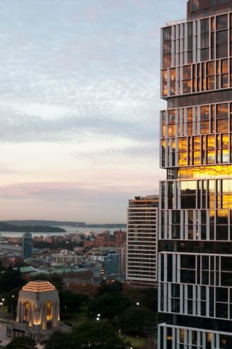 Sydney Australia, Sunset reflecting in glass of highrise apartment building with the Anzac Memorial in Hyde Park and harbour in the background