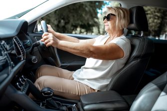 Senior business woman driving a car, view from the inside of a vehicle. Concept of an active people during retirement age