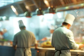 Blurry restaurant kitchen background. Active chefs working. Concept of Culinary chaos, busy kitchen, restaurant ambiance, kitchen staff, professional chefs, culinary teamwork, fast-paced environment.