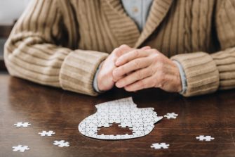 Cropped view of senior man playing with a puzzle of a head