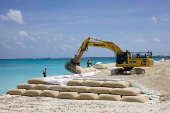 Bulldozer places sand bags on beach in Funafuti