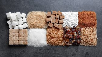 Flat lay composition with different types of sugar on gray background