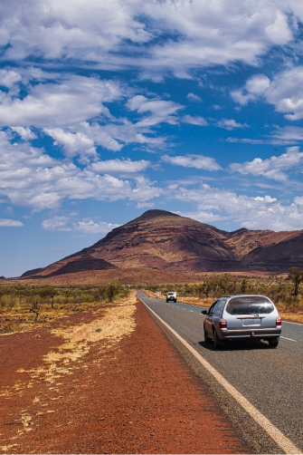 A station wagon travels on a long mostly empty road in outback Australia