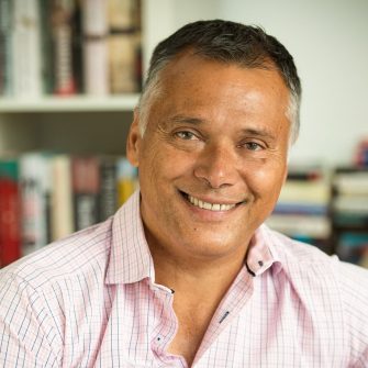 Former ABC journalist Stan Grant smiles in front of a bookshelf