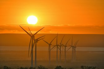 Large wind turbines in silhouette against an orange sky