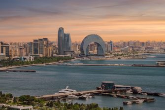 The Crescent Development Project features distinct modern architecture, including the Crescent Hotel, set against a beautiful sunset on the Caspian Sea coast in Baku, Azerbaijan