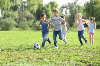 Cute little children playing football outdoors