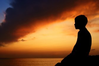 Silhouette of boy on sea sunset