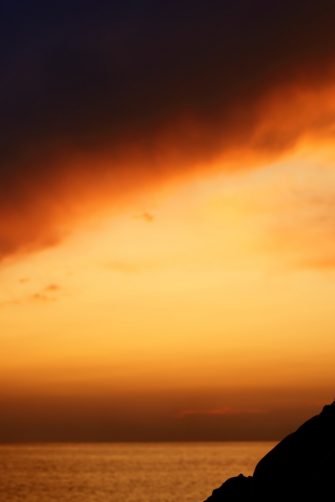 Silhouette of boy on sea sunset