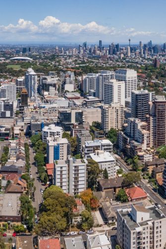 An aerial shot of an area of Western Sydney characterised by houses set closely together with narrow roads, little vegetation and dark roofs