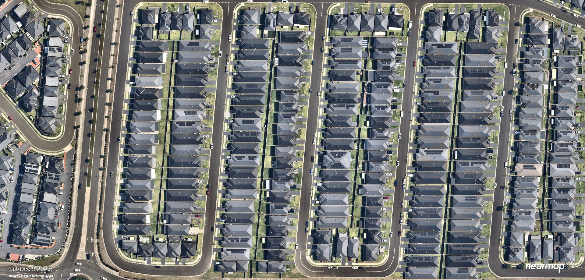 An aerial shot of an area of Western Sydney characterised by houses set closely together with narrow roads, little vegetation and dark roofs