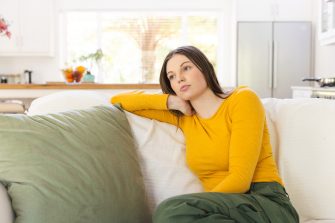 Portrait of thoughtful caucasian woman sitting on couch on in living room at home, copy space