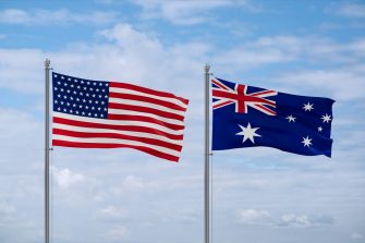 Australia and USA flags waving together on blue cloudy sky, two country relationship concept