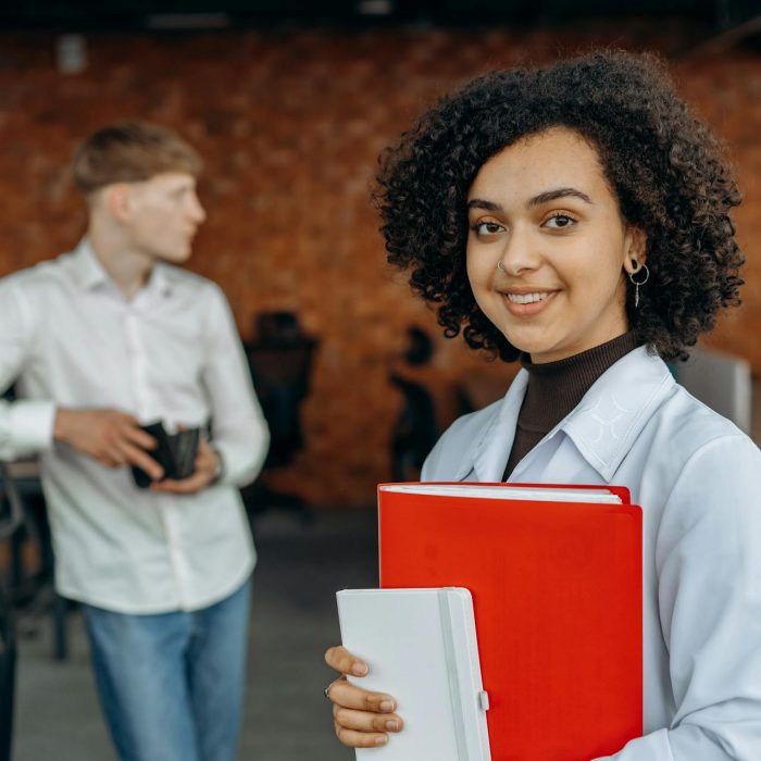 Female student looking at the camera holding a red book