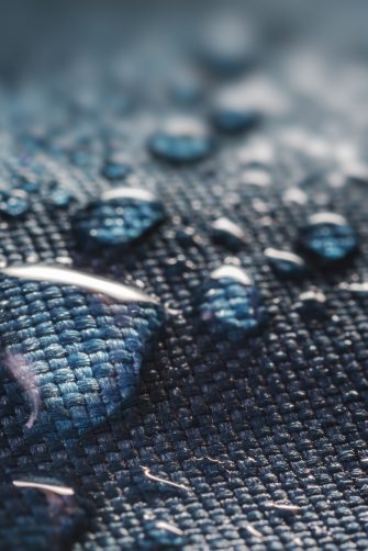 Water droplets sitting on top of a water resistant material. Materials such as rain coats can contain PFAS chemicals.