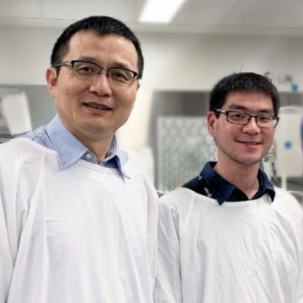 Two research students in lab coats smiling at the camera