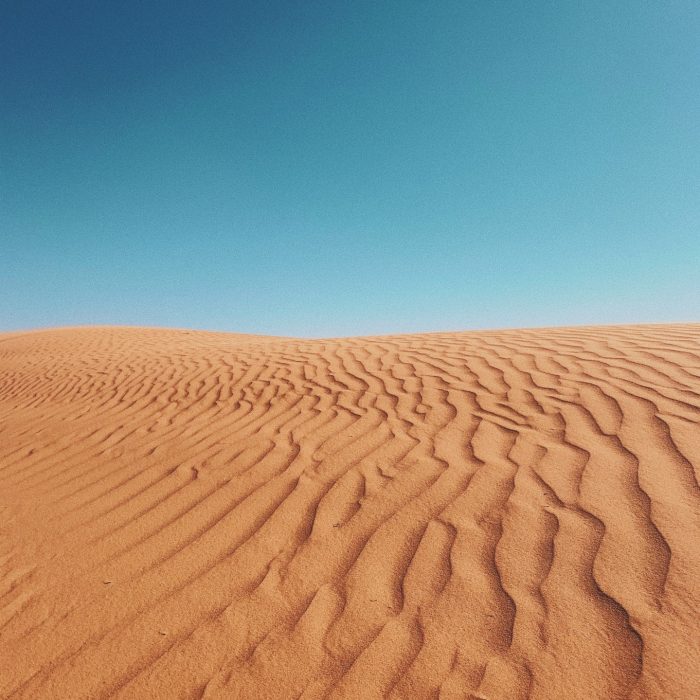 Red sand dunes under a clear blue sky