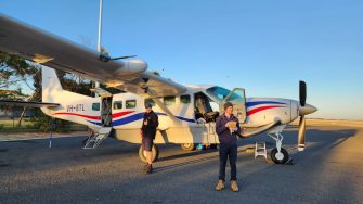 Two people standing outside a light aircraft