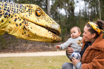 Baby in front of fake dinosaur