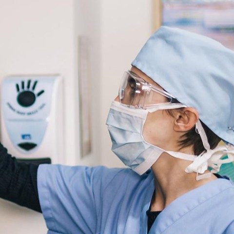 Woman in scrubs getting medical supplies from a shelf