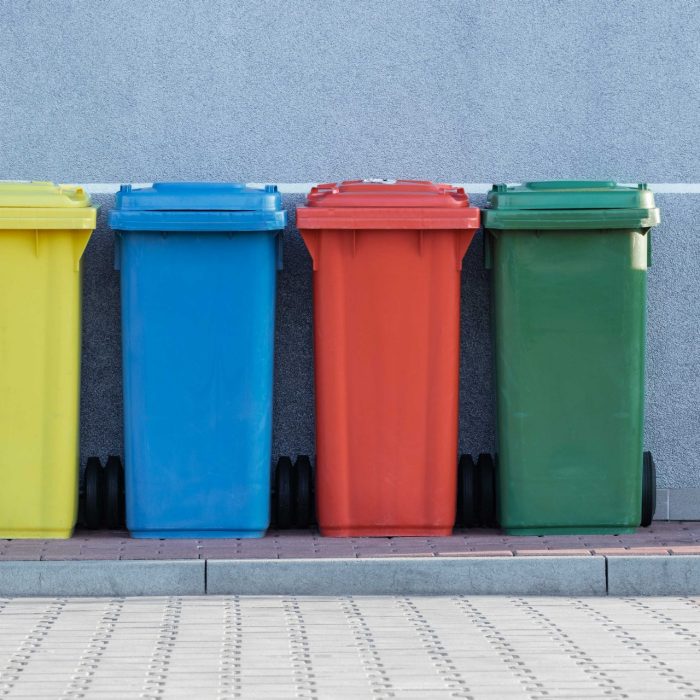 Four coloured bins in front of a grey wall